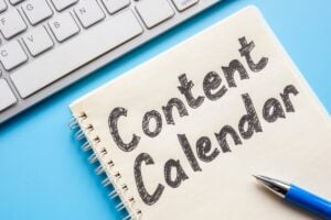 Notebook with words ''Content Calendar'' pen and keyboard.