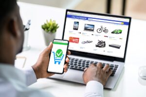 Man using phone and laptop while shopping online.