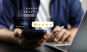 Man holding phonw as he checks client reviews, as well as using his laptop.
