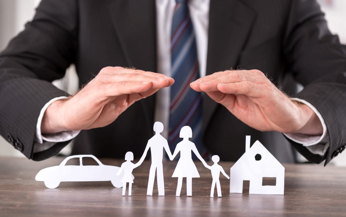 Man using his hands in a covering position over paper family on desk.