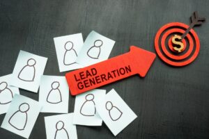 Paper squares with person figure and big red arrow on desk with word ''LEAD GENERATION'' pointing at spiral.