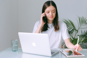 Woman using laptop while talking on the phone.