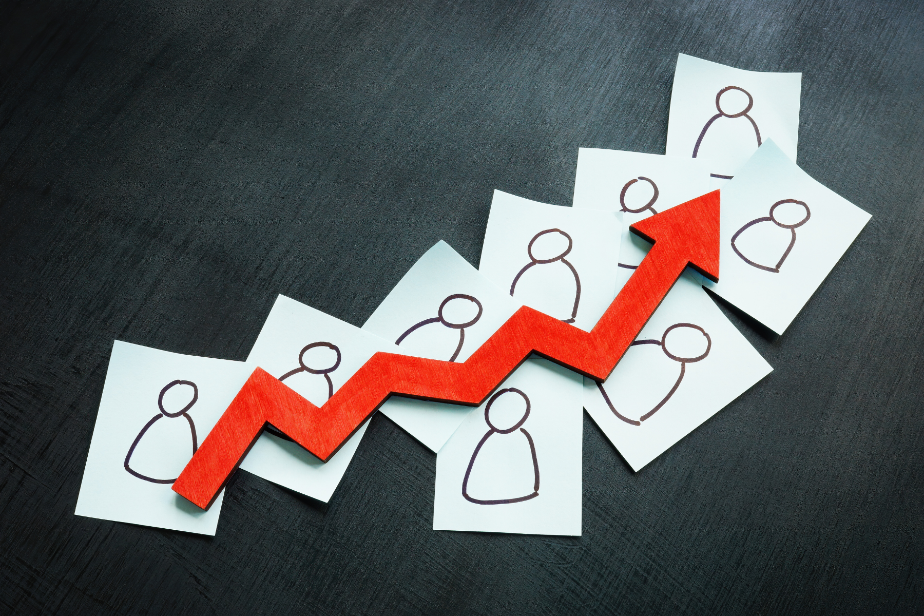 Drawings of people on multiple sheets of paper with red arrow increasing, lead generation concept.