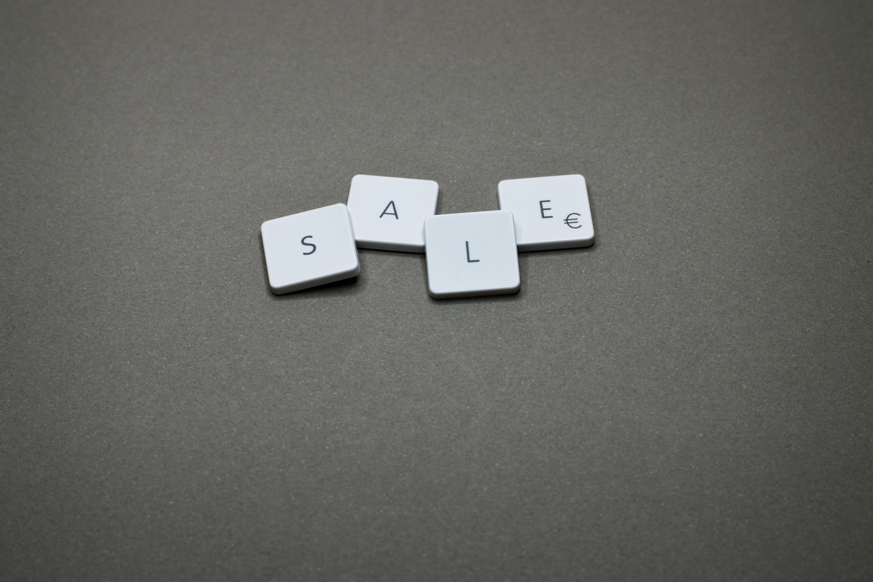 Four white tiles spelling out the word 'SALE' on a gray background.