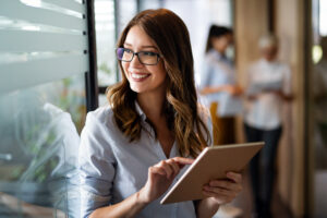 Young happy business woman working with tablet in corporate office. Business people concept