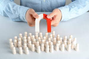 Man with magnet attracting game pieces at white.