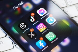 Smartphone screen displaying a folder labeled “Social” with app icons including Threads, TikTok, Messenger, Telegram, X, Instagram, WhatsApp, and Facebook, each with notification badges.
