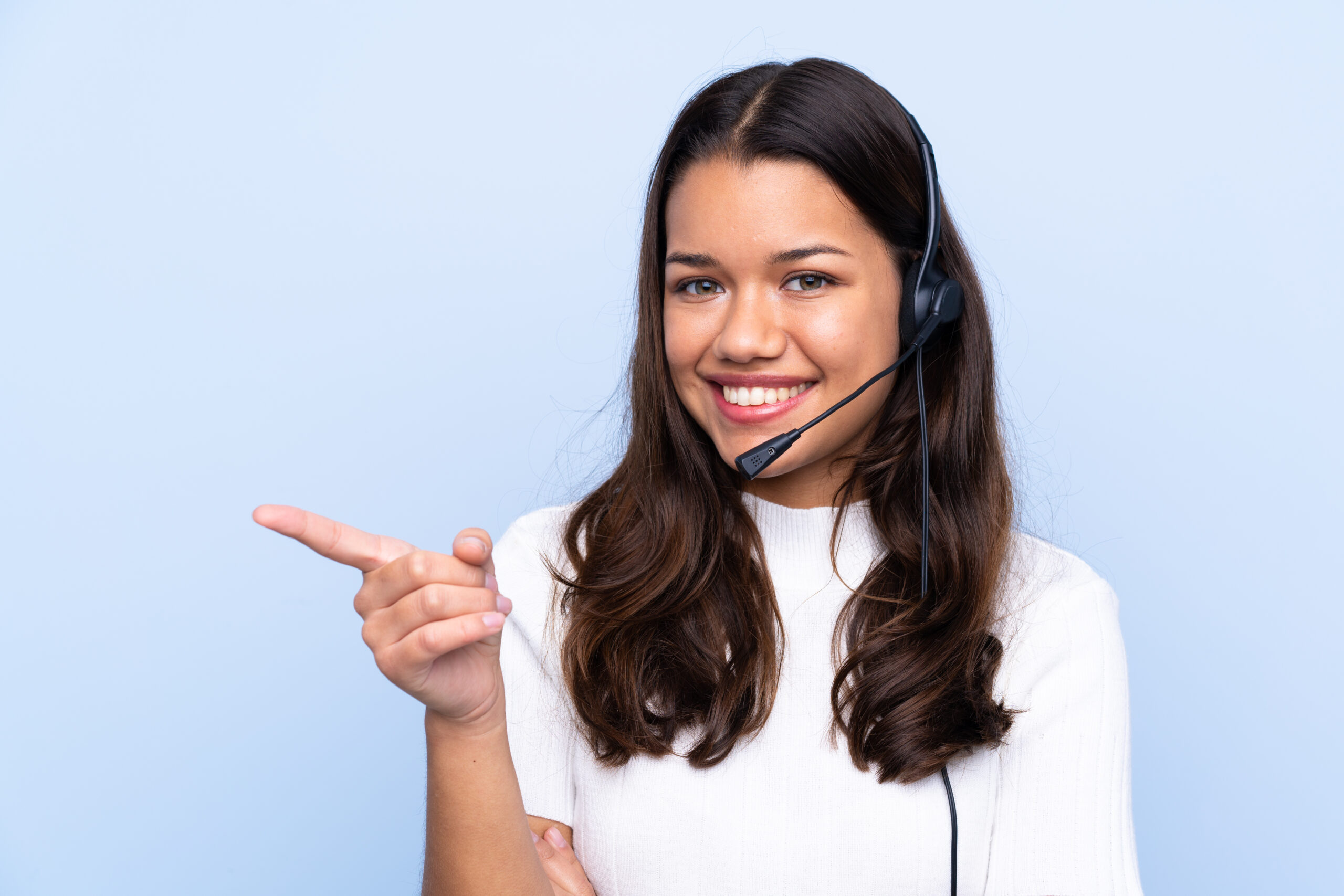 Telemarketer woman over isolated blue background pointing finger to the side