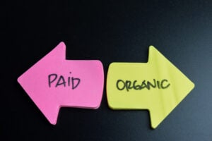 Concept of Paid or Organic write on sticky notes isolated on Wooden Table.