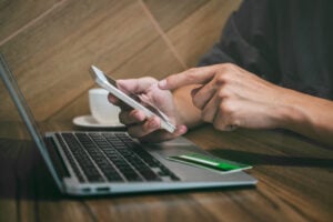 Businessman holding credit card and using smartphone and laptop.