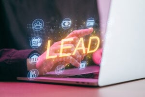 A person is working on a laptop with a focus on the word lead.