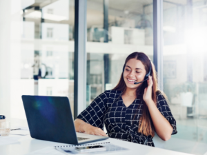Woman telemarketer using headset and laptop on office space.